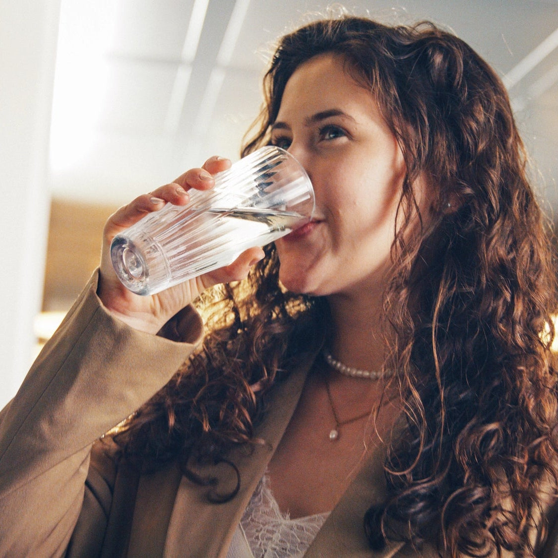 Vrouw die binnen water drinkt, met een wazige achtergrond